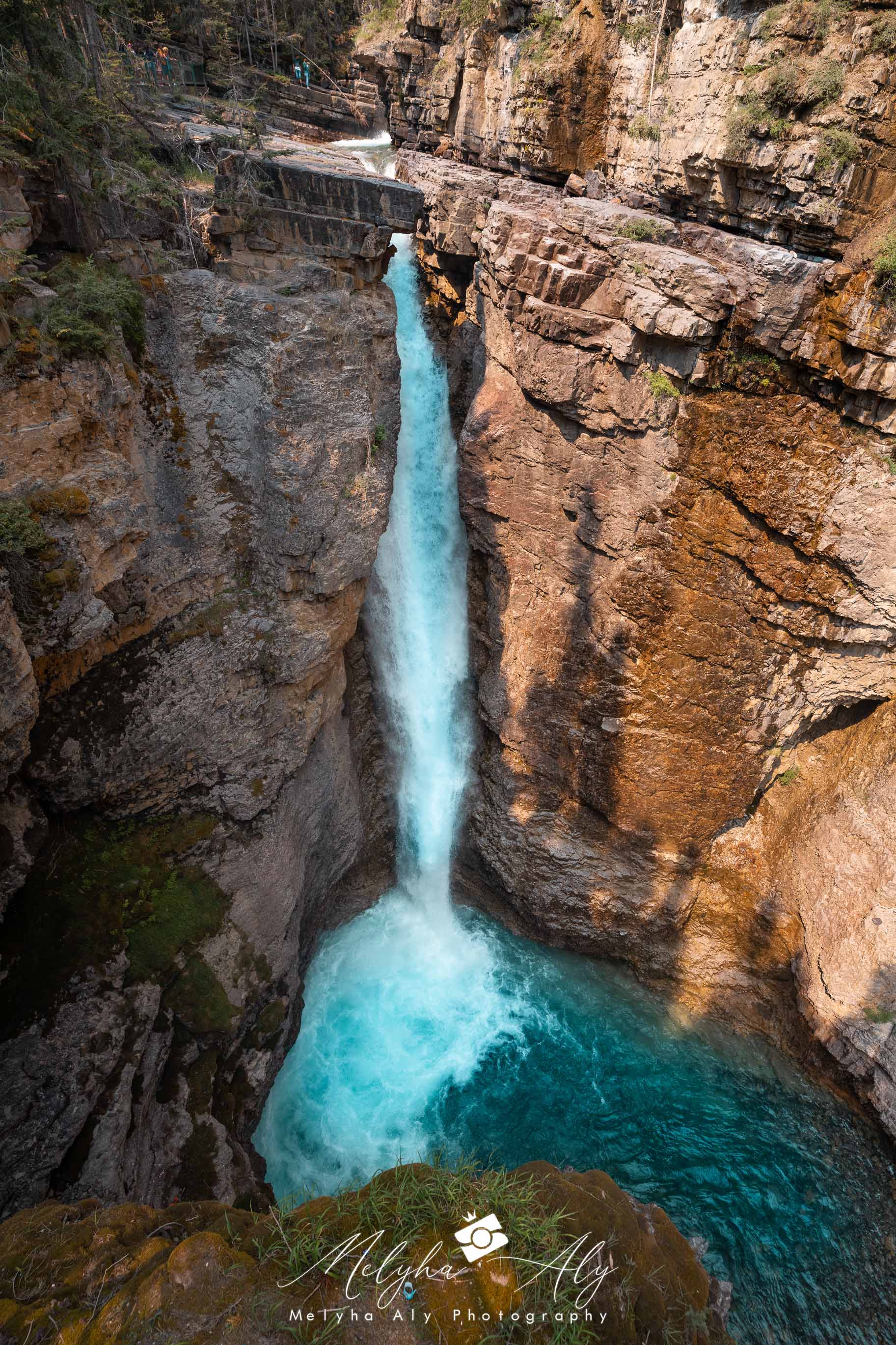Vertical shot of waterfalls flowing through Johnston Canyon's rocky terrain